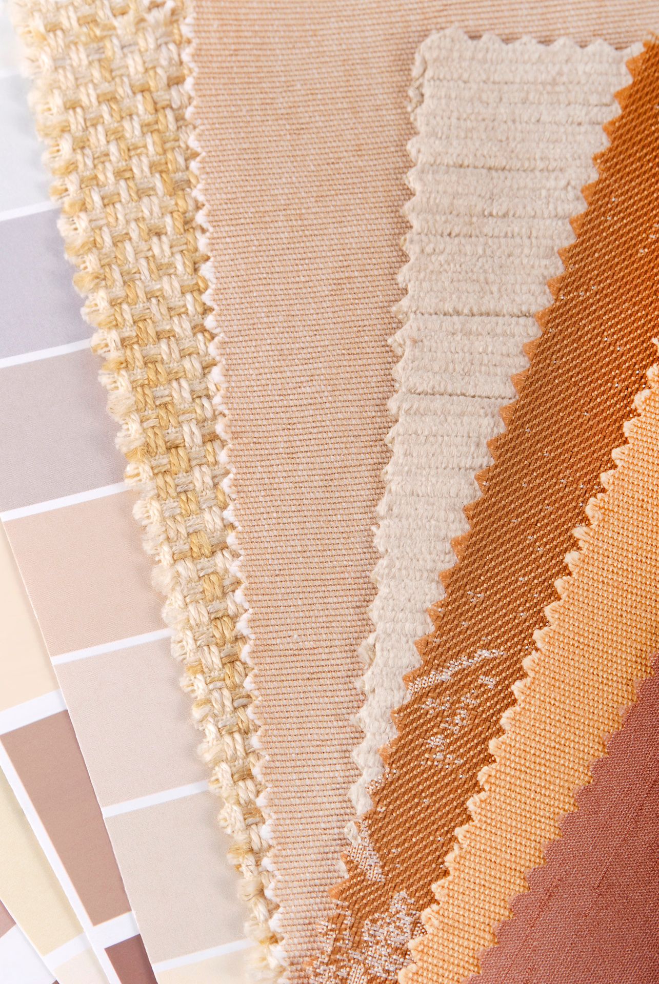 Un primer plano de una pila de muestras de tela junto a una paleta de pintura.