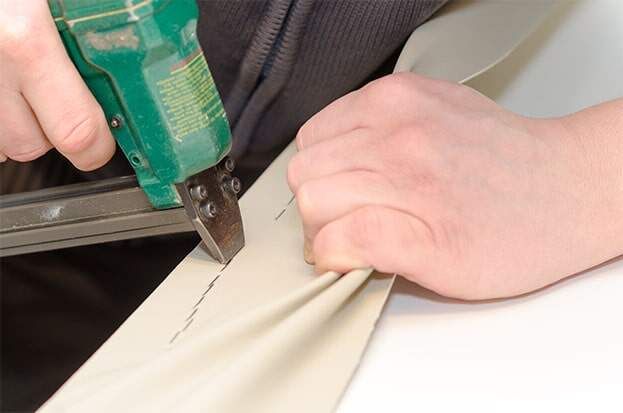 Una persona está usando una grapadora en un trozo de tela.