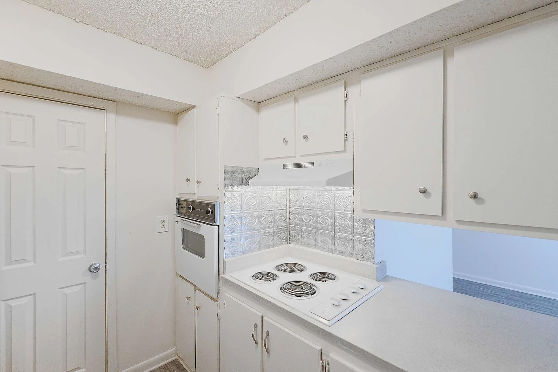 A kitchen with white cabinets and a stove top oven.