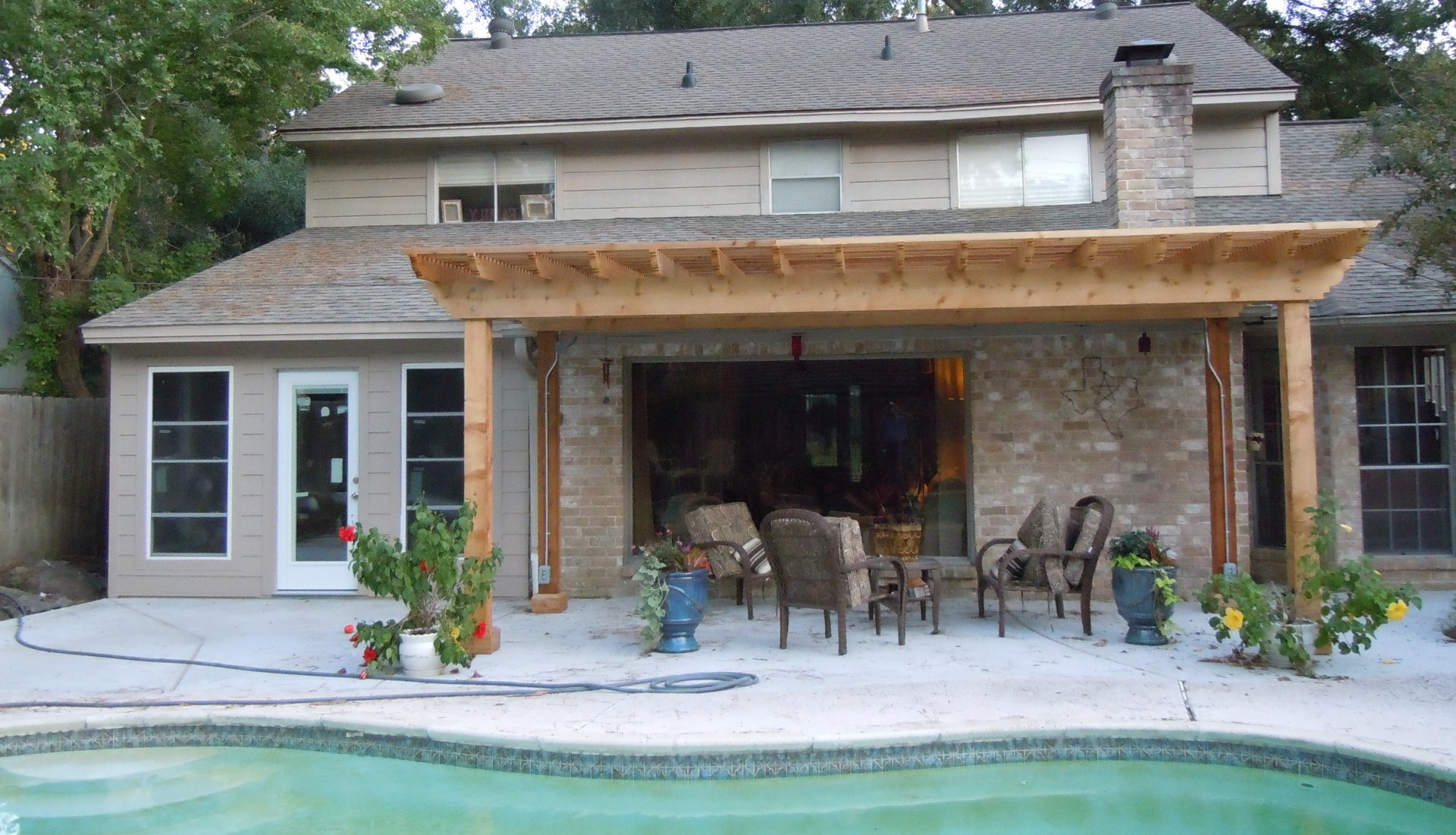 A house with a patio and pergola with a pool in front of it
