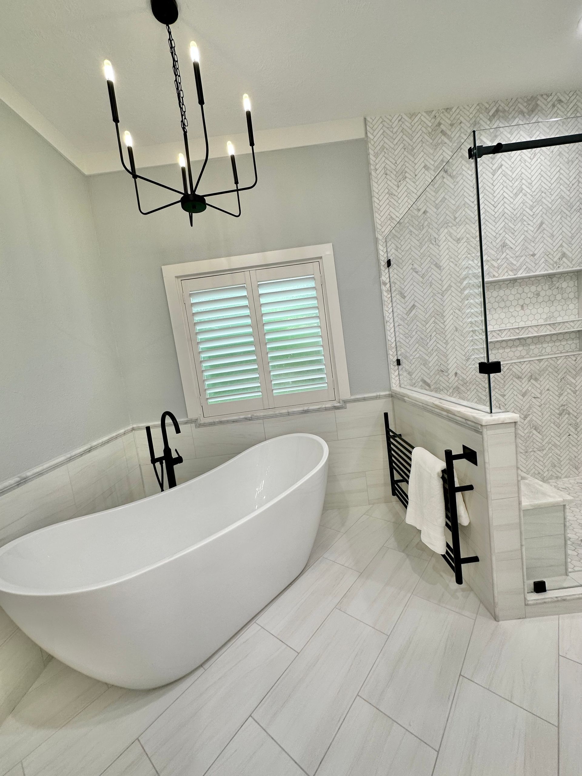 A bathroom with a bathtub and a shower with a chandelier hanging from the ceiling.