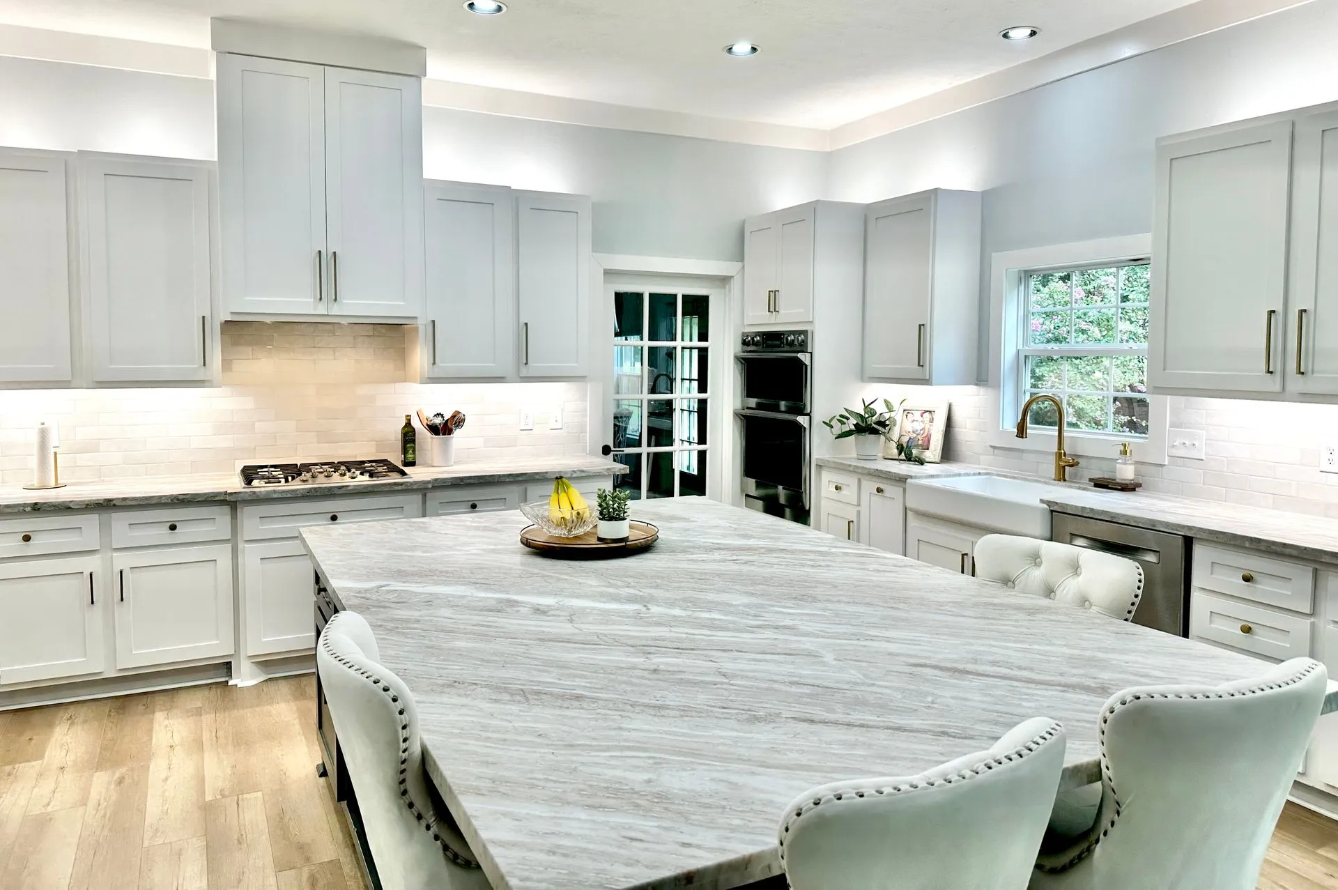 A kitchen with white cabinets , granite counter tops , and a large island.