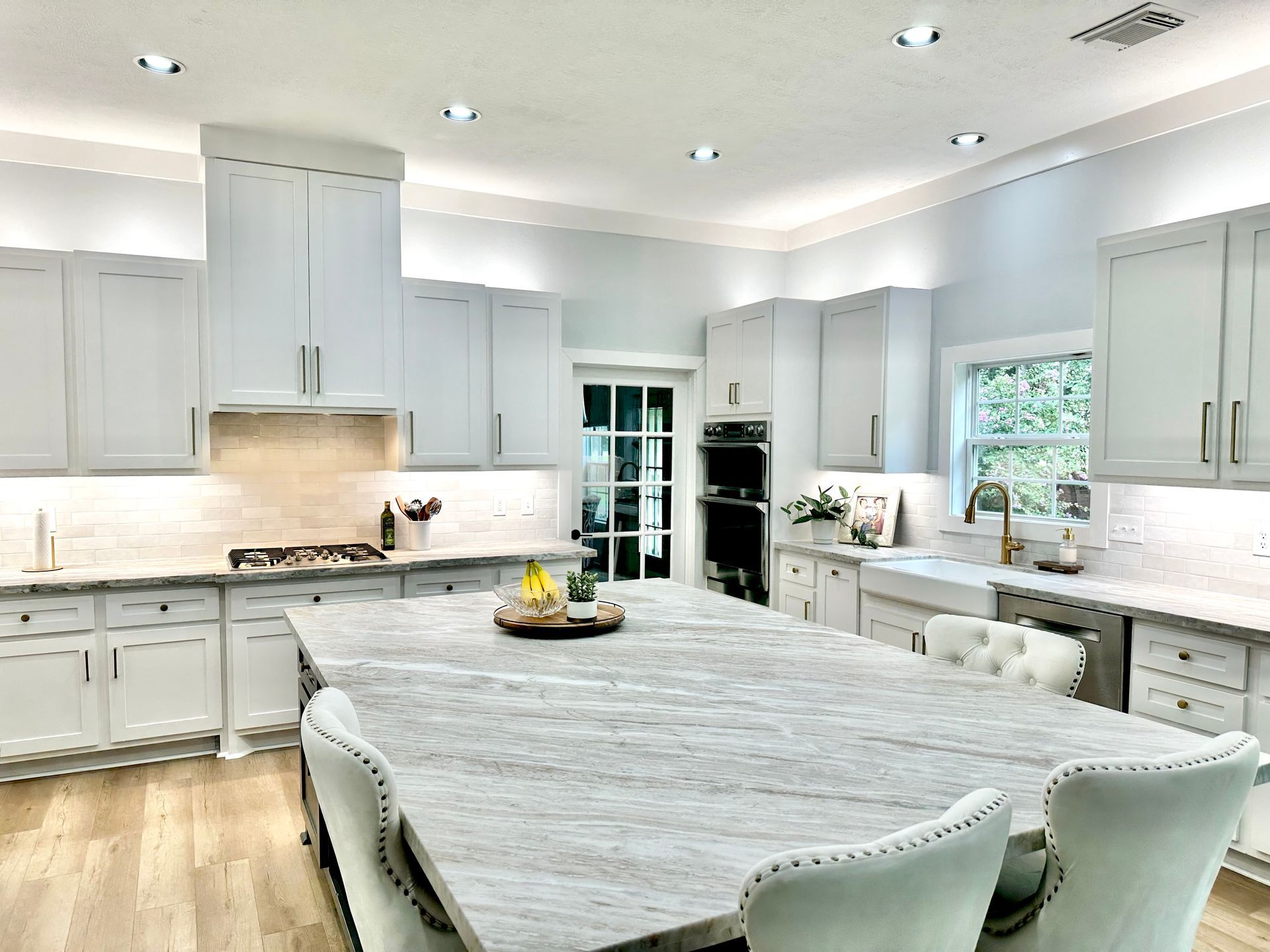 A kitchen with white cabinets , granite counter tops , and a large island.