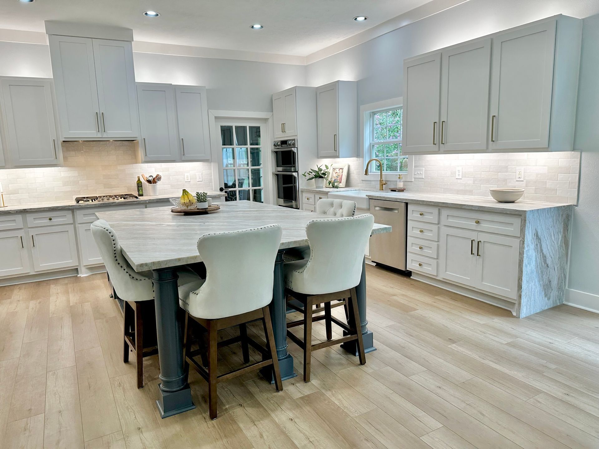 A kitchen with white cabinets and a large island in the middle