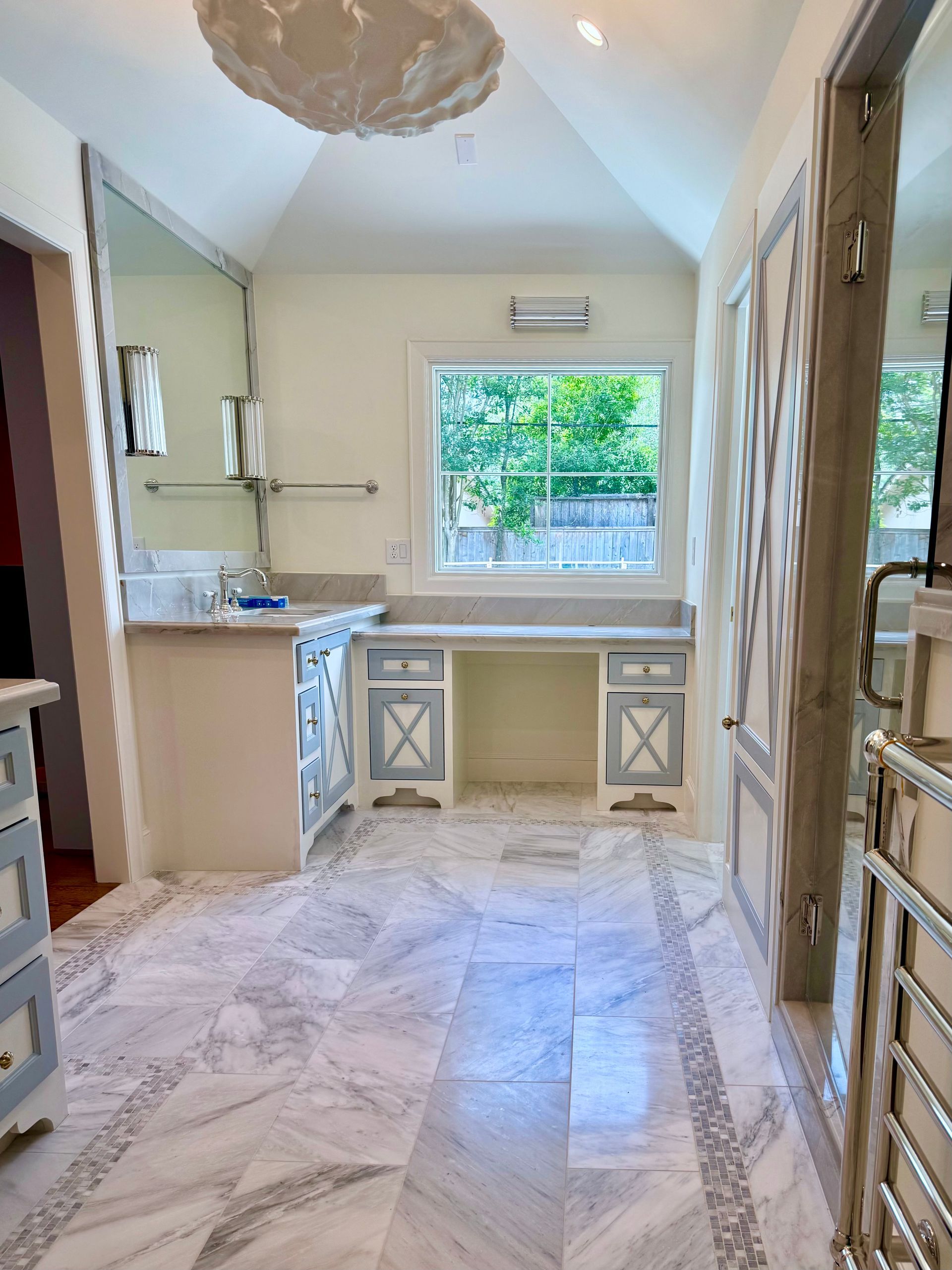 A bathroom with marble floors and white cabinets