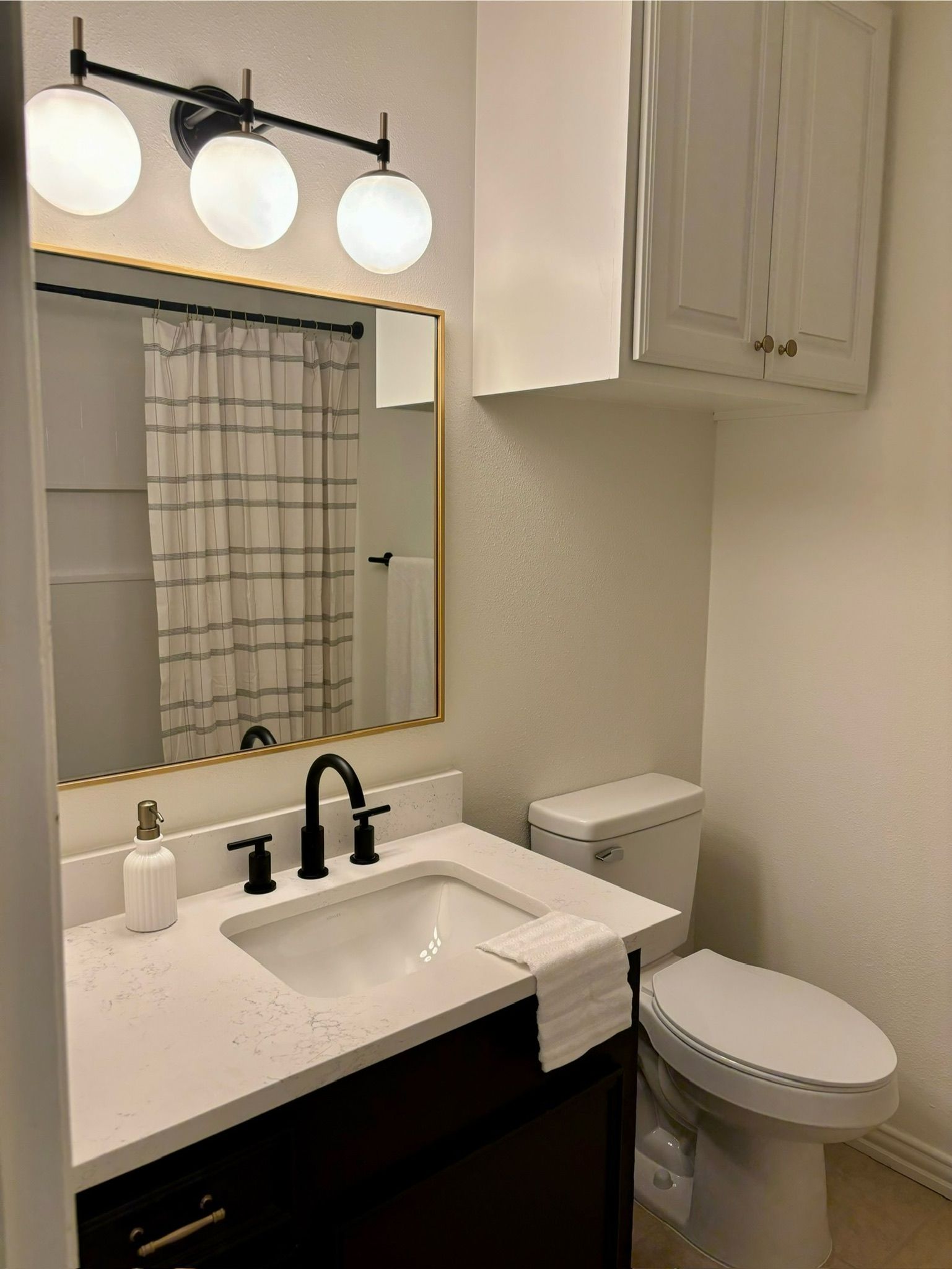 A bathroom with a sink , toilet and mirror.