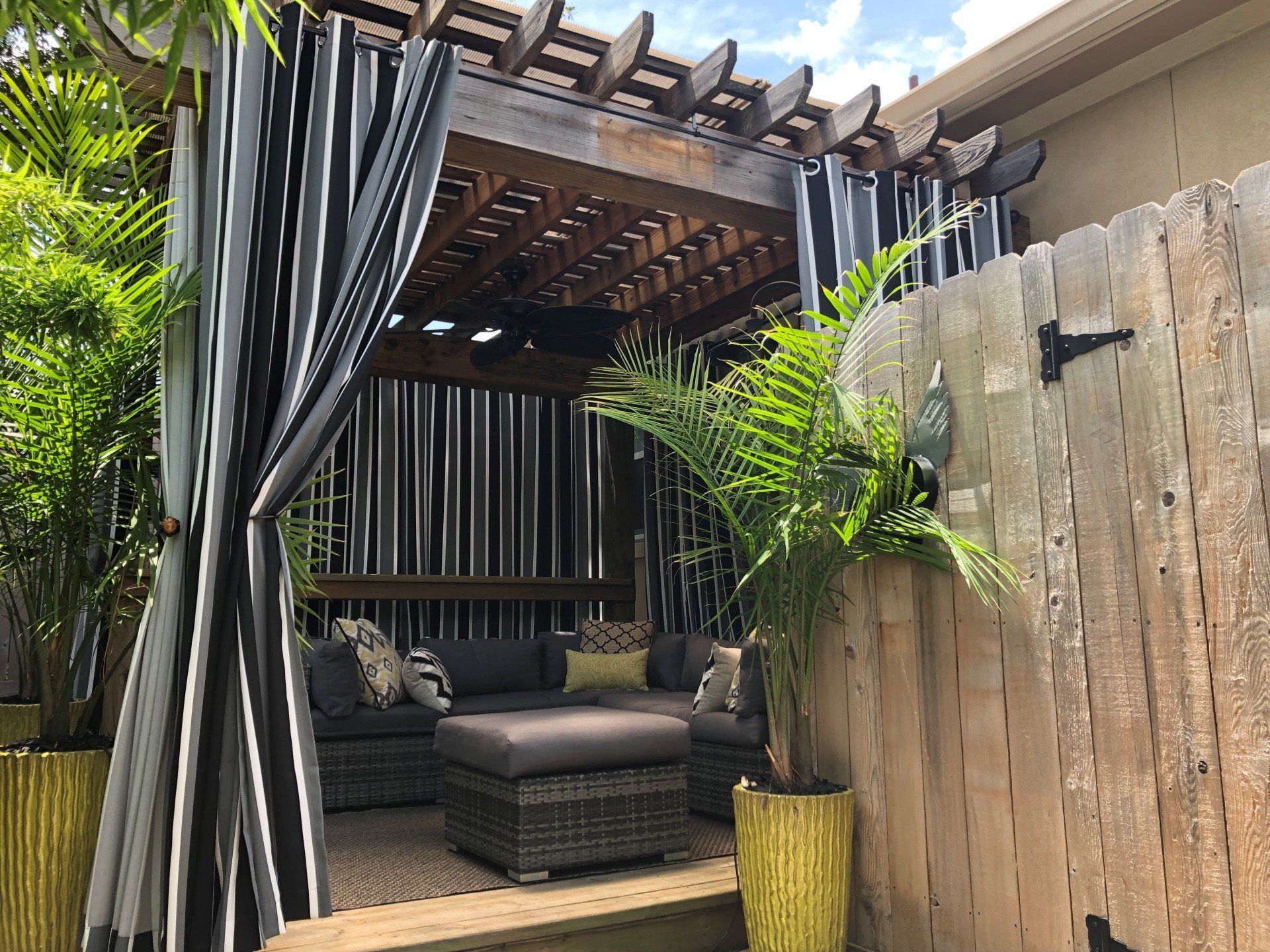 A pergola with black and white curtains and a couch underneath it.