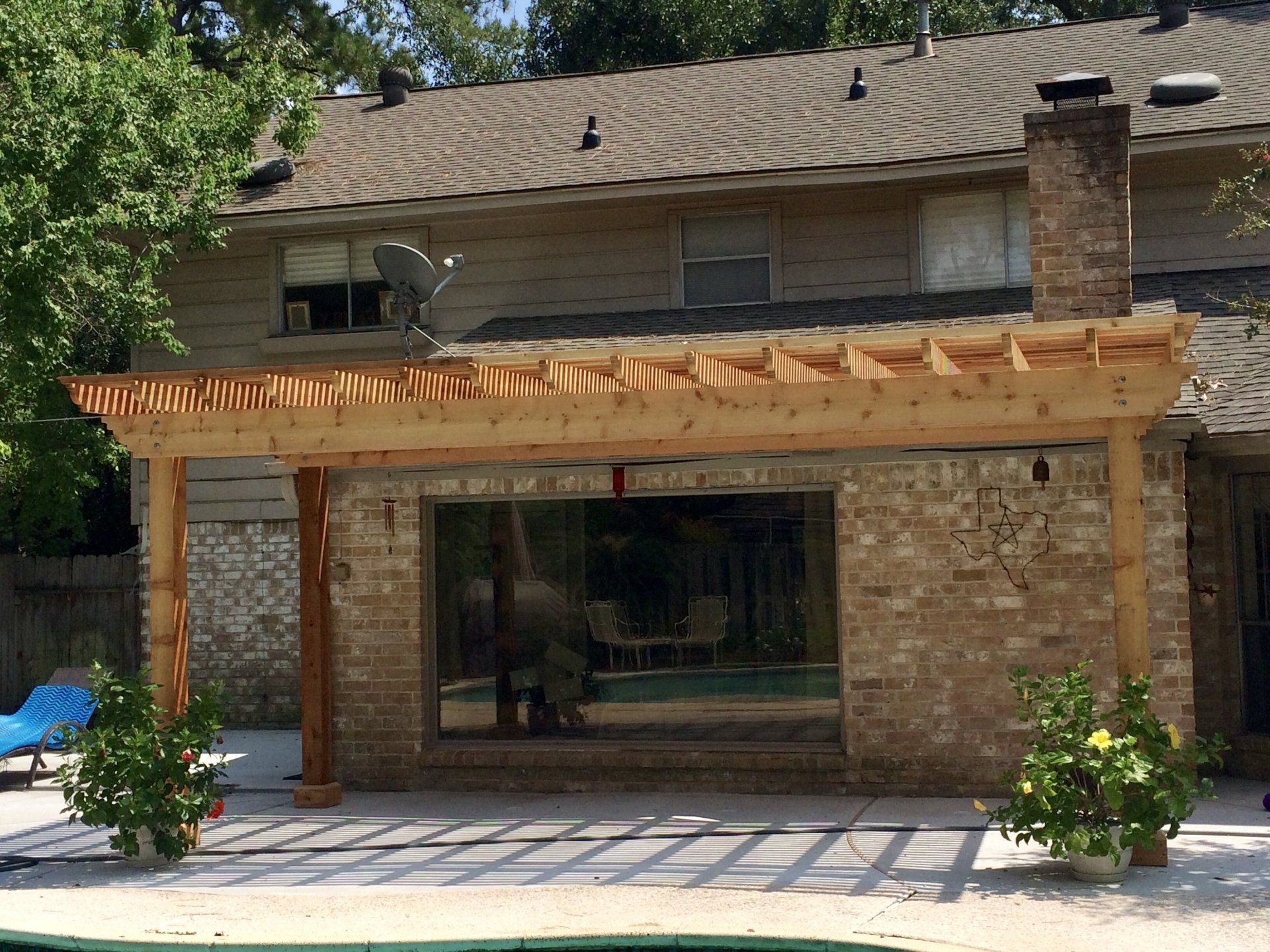 A wooden pergola attached to a brick house