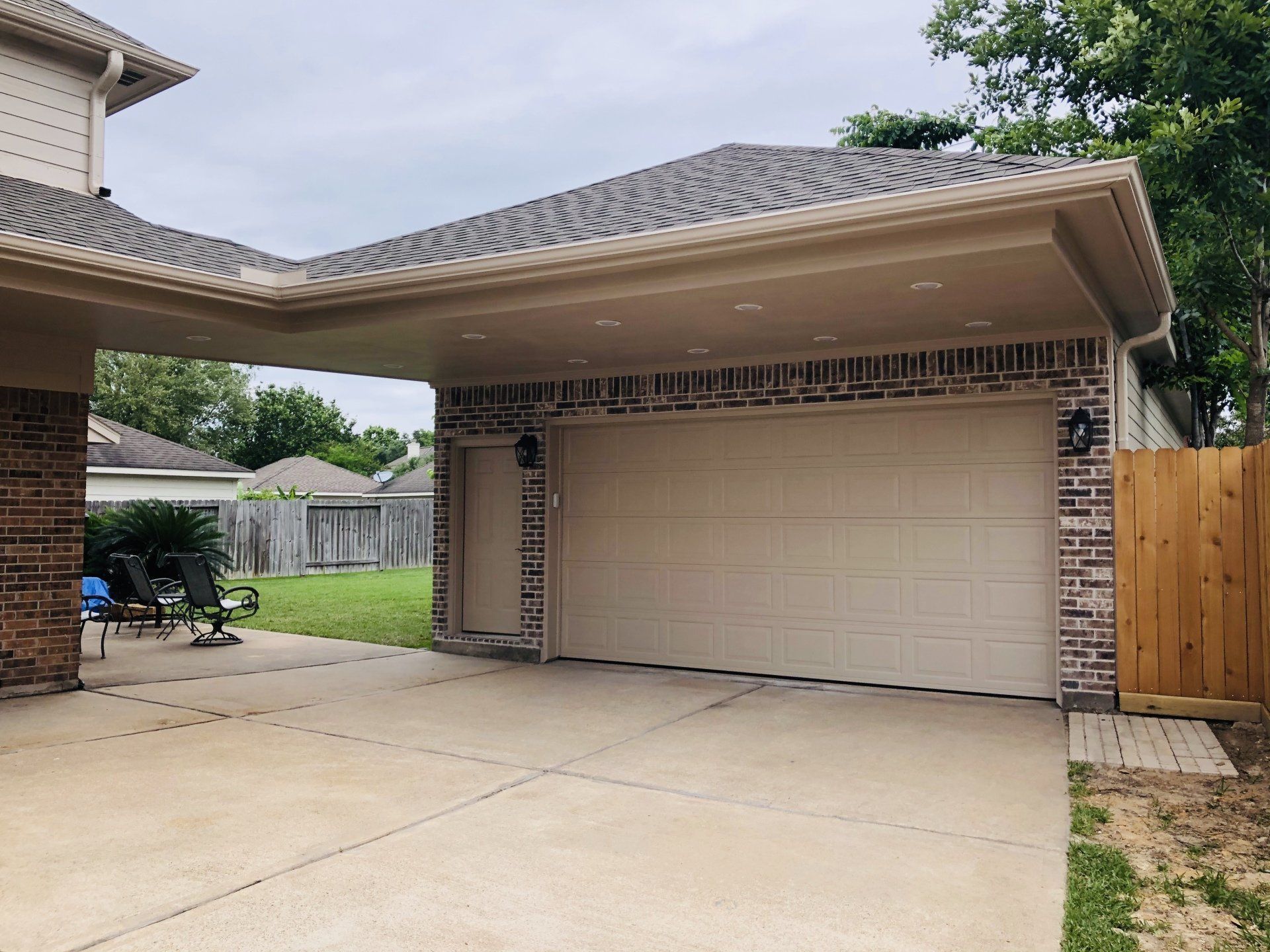 A covered attached garage in front of a brick house.