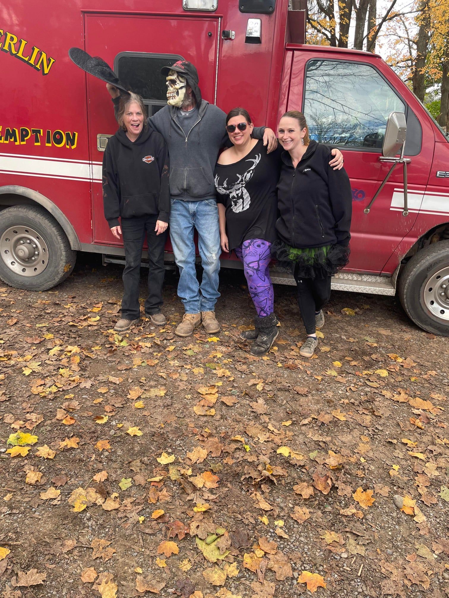 A group of people are posing for a picture in front of a red van.