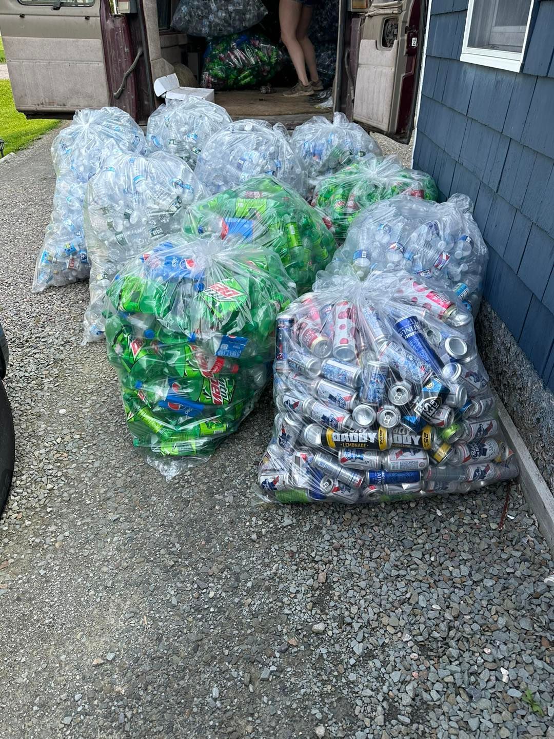 A bunch of bags filled with aluminum cans are sitting on the side of a road.