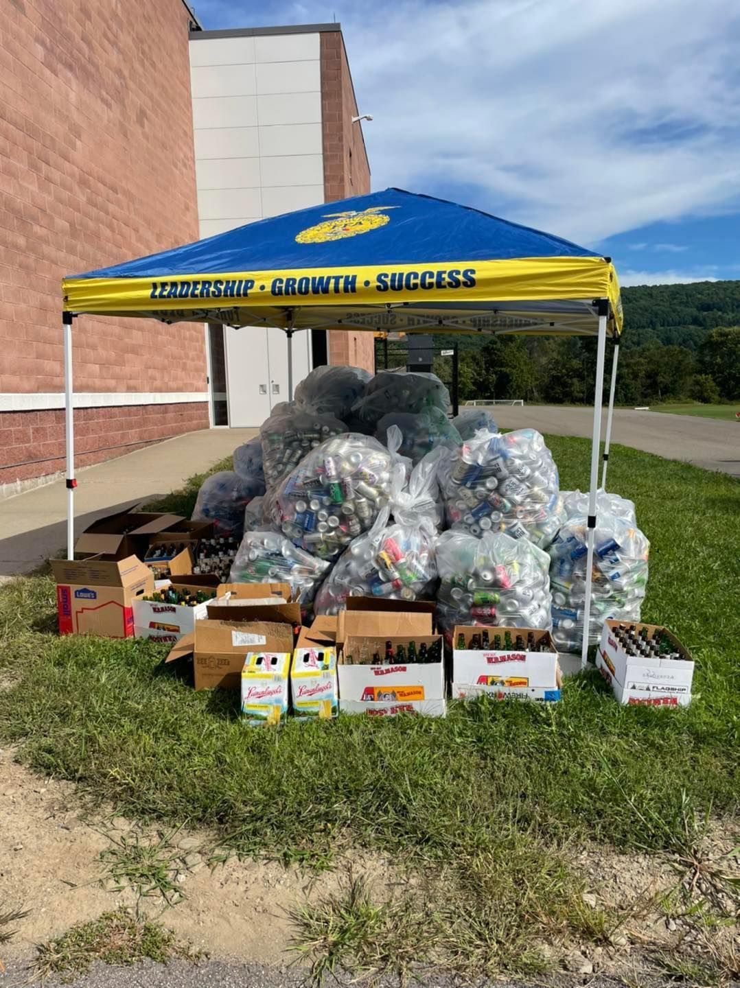 A large pile of bottle caps is sitting under a canopy in front of a building.
