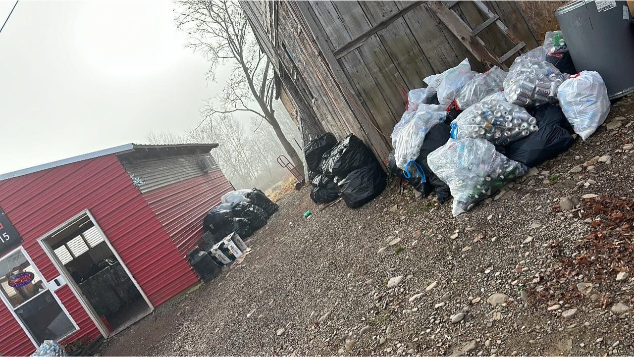 A bunch of bags are sitting on the ground in front of a red building.