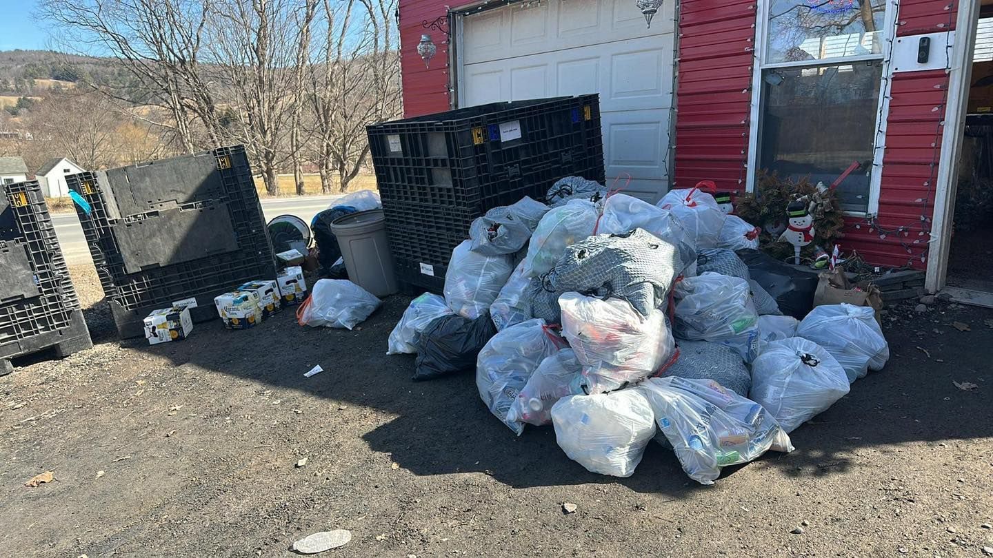 A pile of trash bags is sitting in front of a garage.