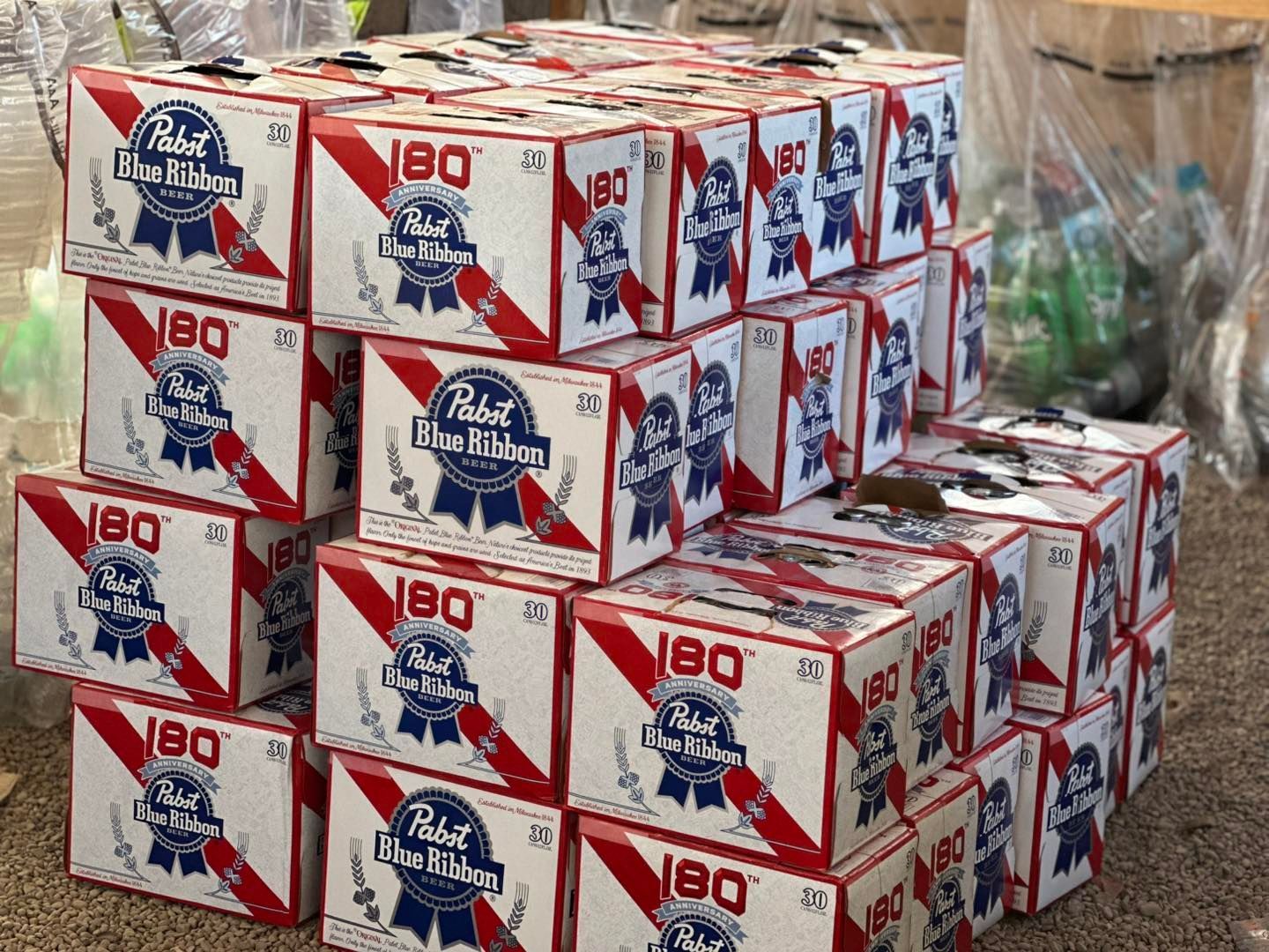 A bunch of boxes of pabst blue ribbon beer are stacked on top of each other.