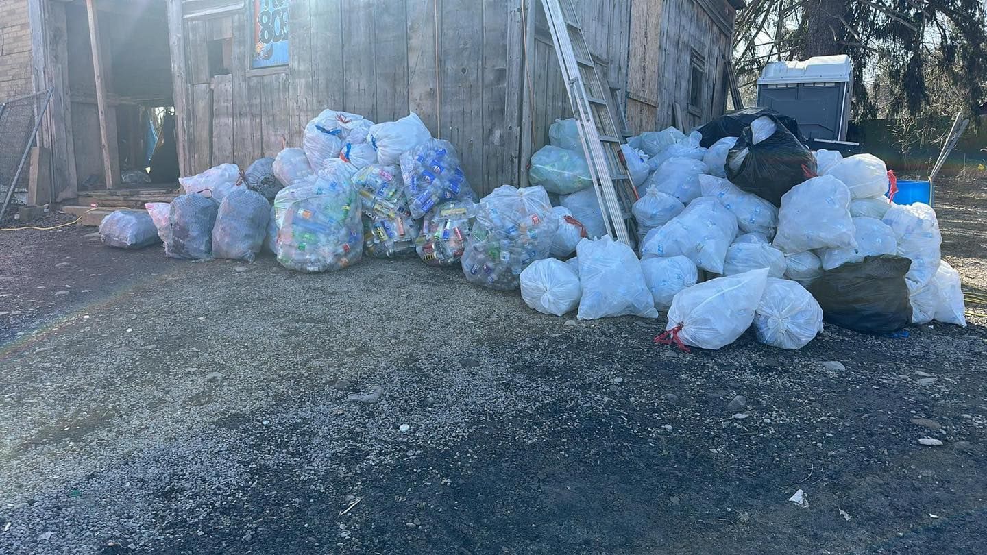 A pile of trash bags sitting on the ground in front of a building.