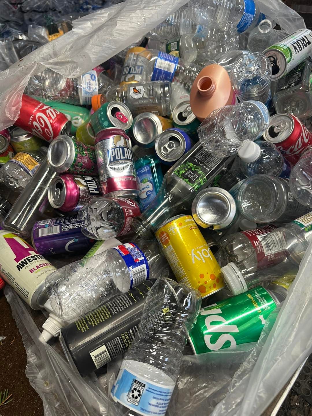 A pile of plastic bottles and cans in a plastic bag.