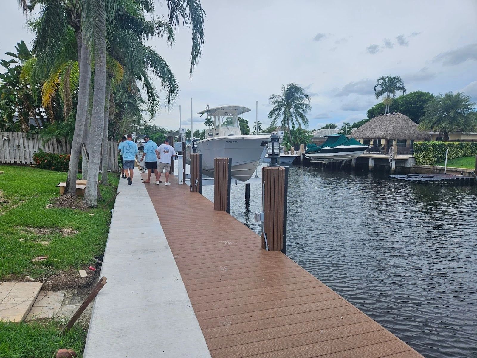 A group of people are walking along a dock next to a body of water.