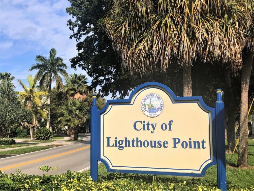 A sign that says deerfield beach with palm trees in the background