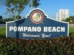 A blue sign that says pompano beach welcomes you