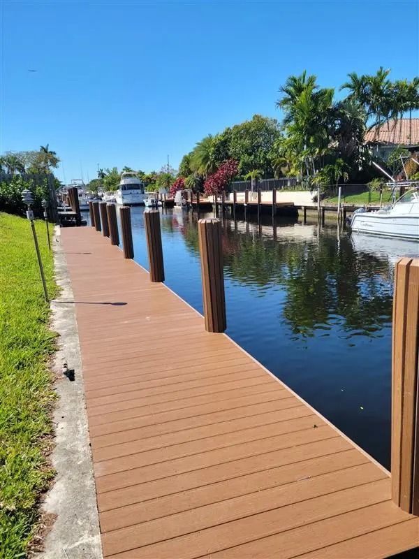 A wooden dock leading to a body of water with boats in it.