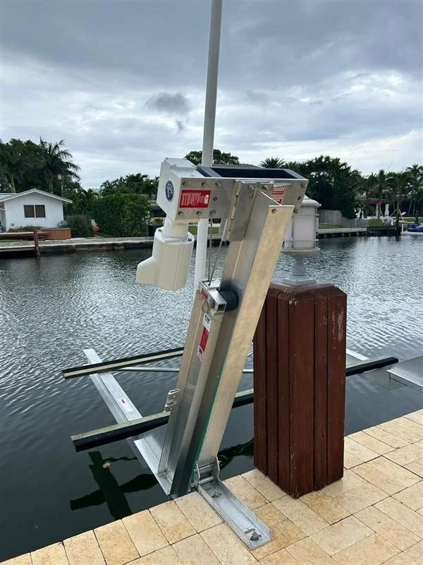 A boat lift is sitting on a dock next to a body of water.