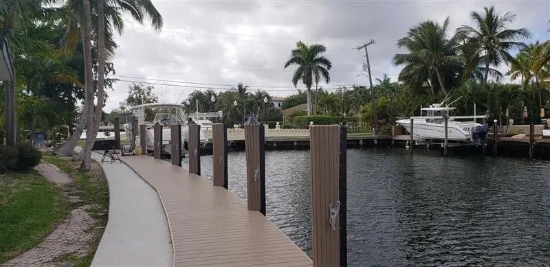 A dock with boats docked in the water and palm trees in the background.