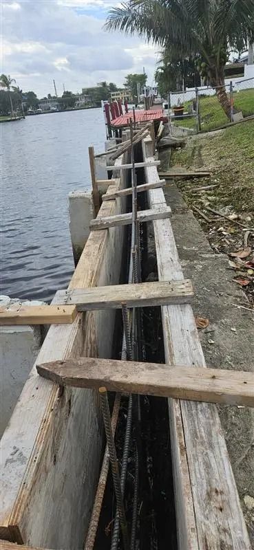 A concrete wall is being built next to a body of water.