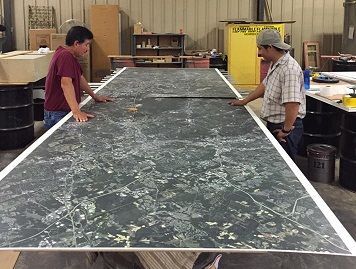 Two men are standing next to a large marble table.
