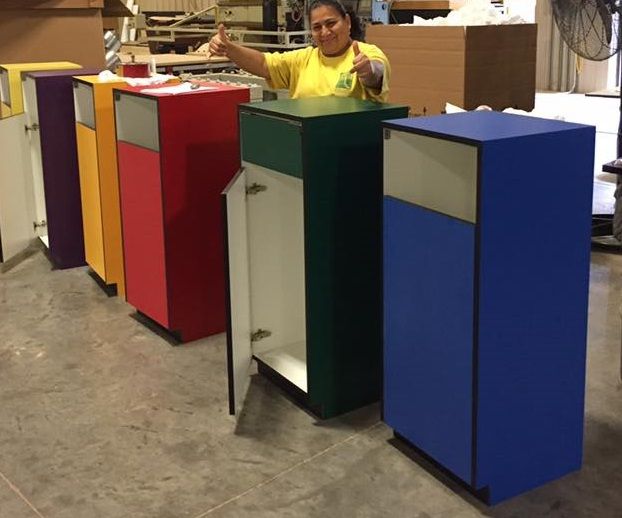 A woman in a yellow shirt is standing in front of a row of colorful cabinets