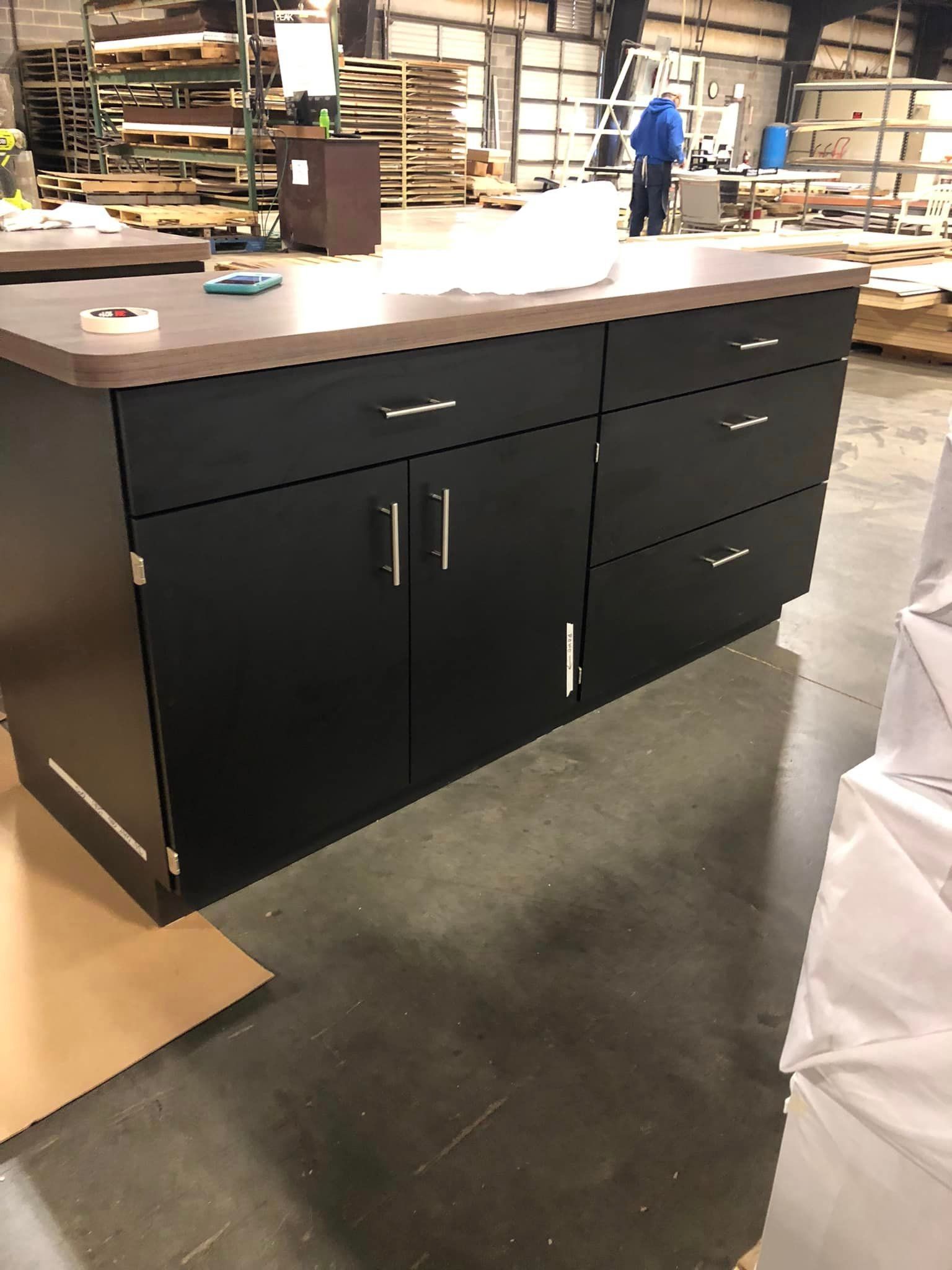 A large black cabinet with drawers and doors is in a warehouse.