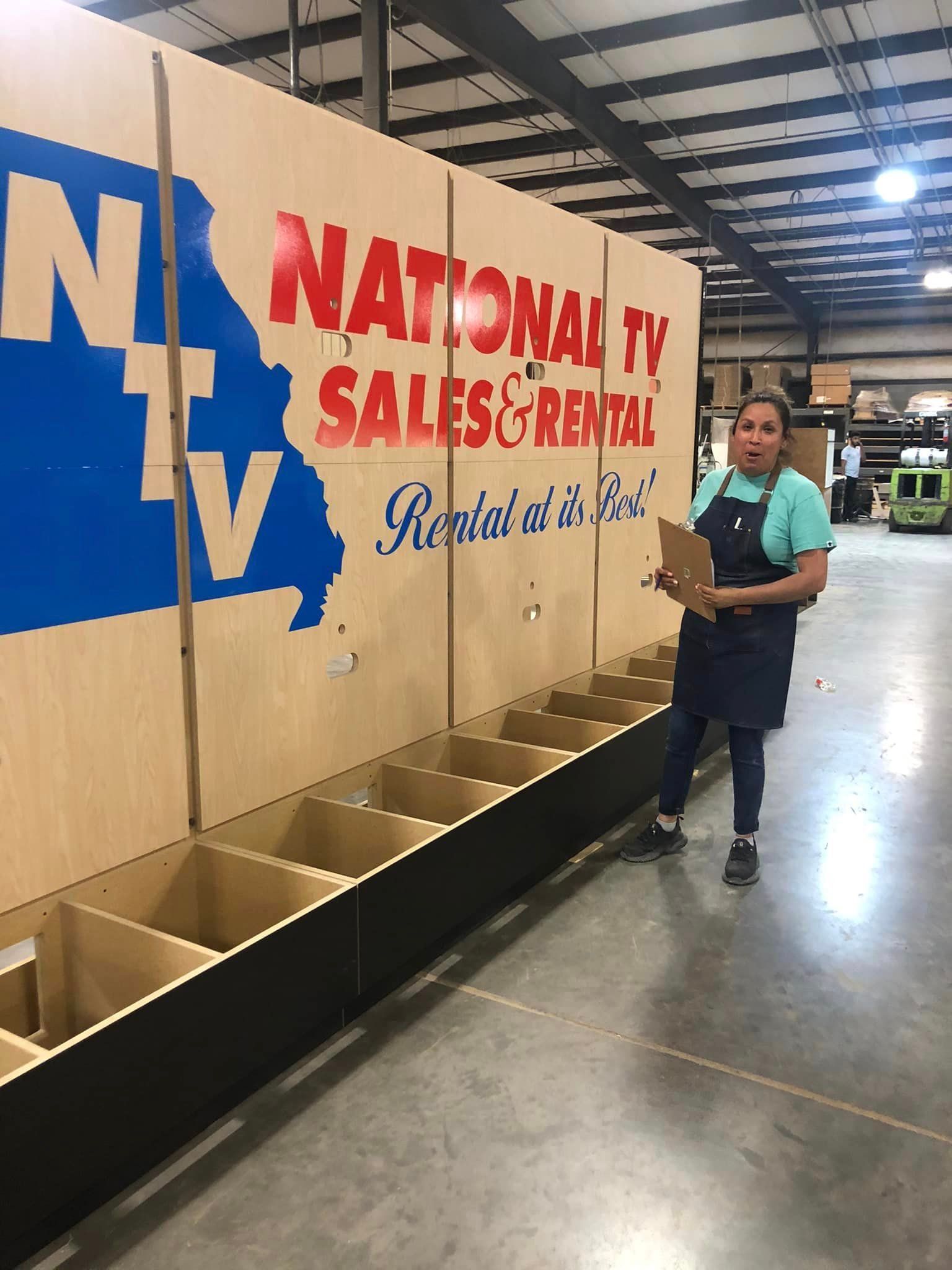 A woman is standing in front of a wall that says national tv sales & rental