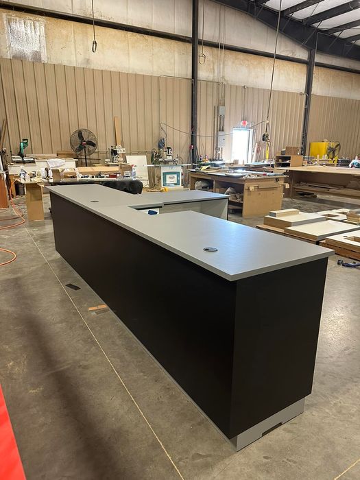 A long black counter in a warehouse with a gray counter top.
