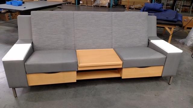 A grey couch with a wooden table underneath it in a warehouse.