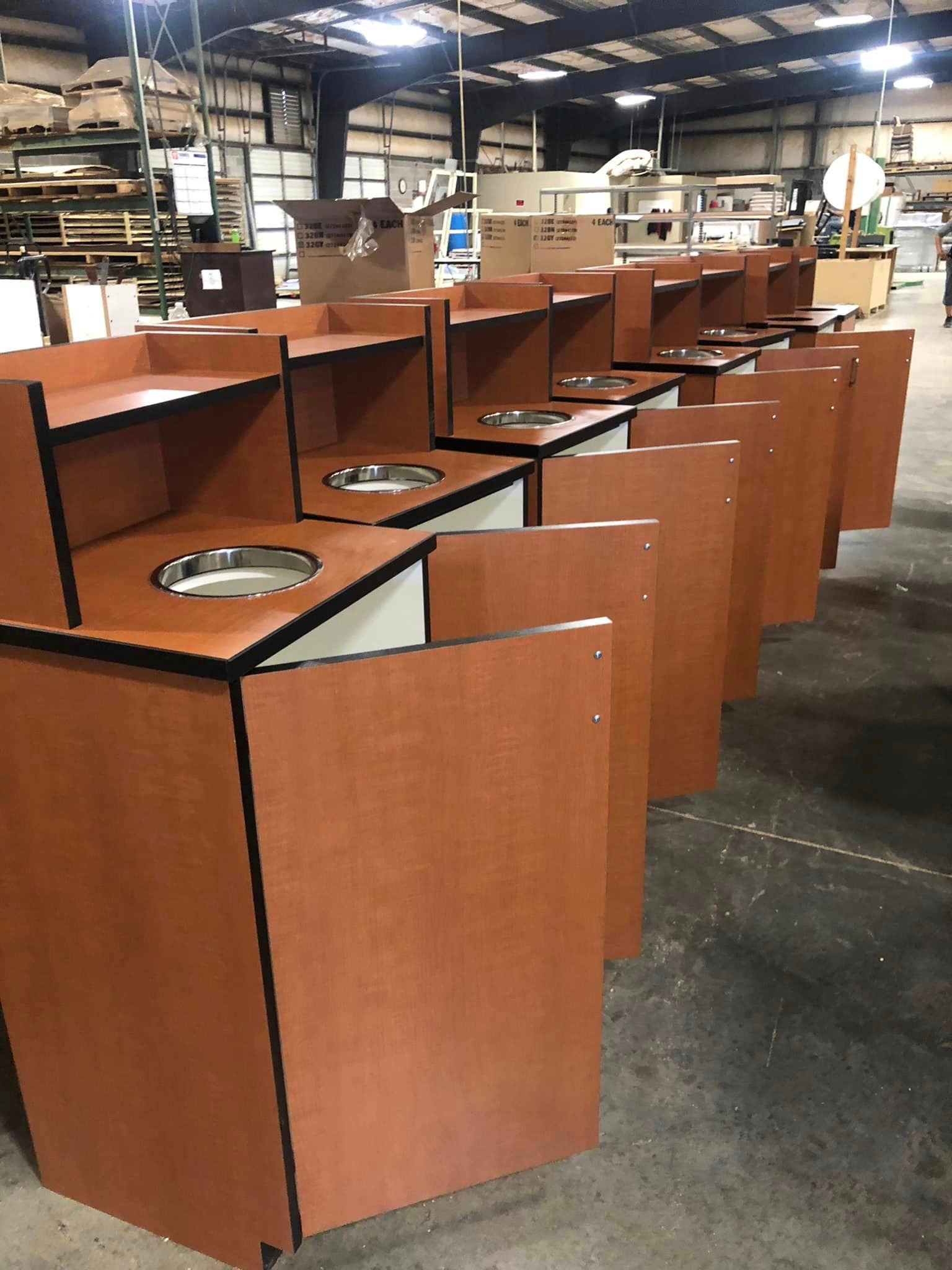 A row of wooden trash cans are lined up in a warehouse
