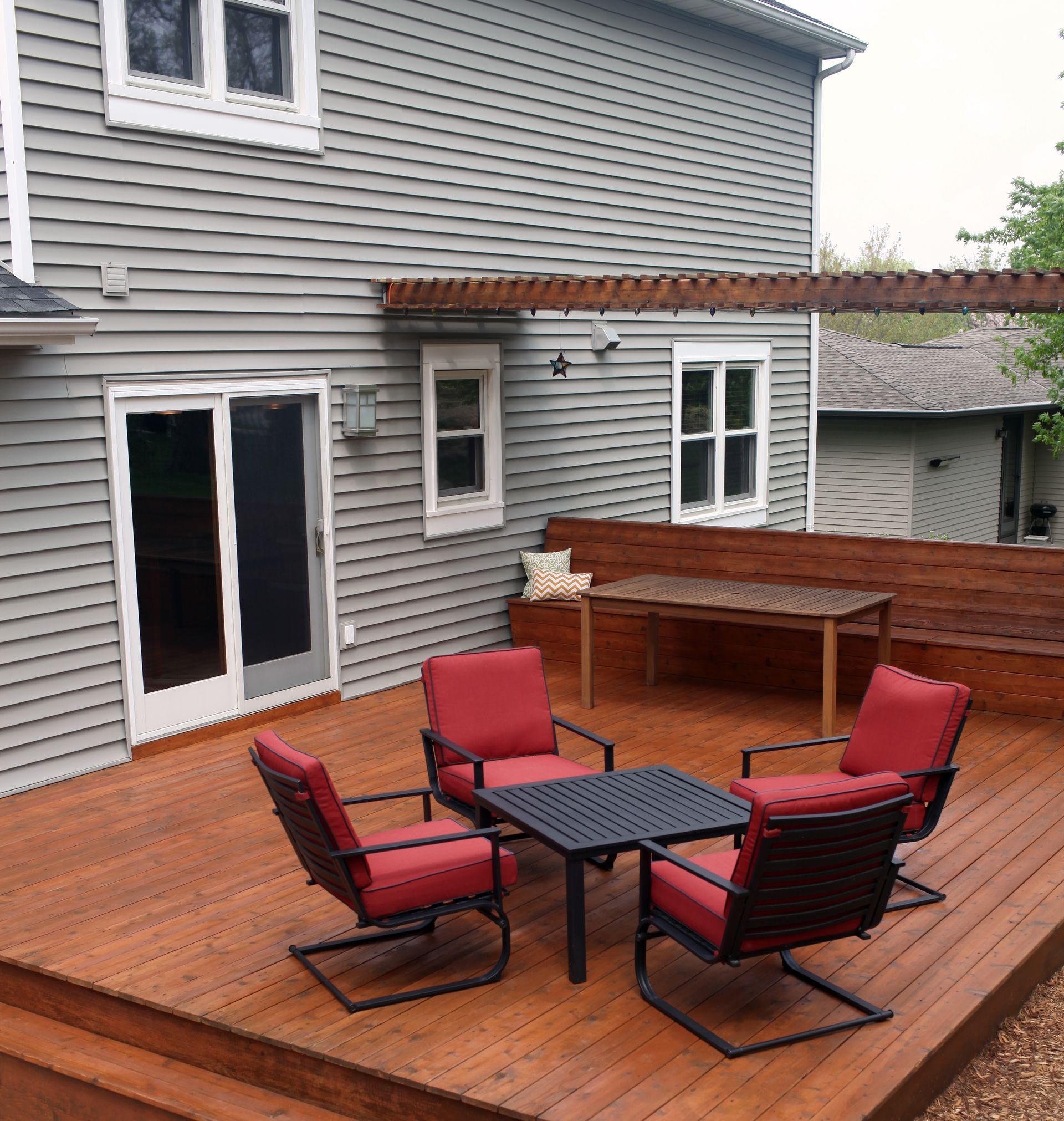 A wooden deck with chairs and a table in front of a house