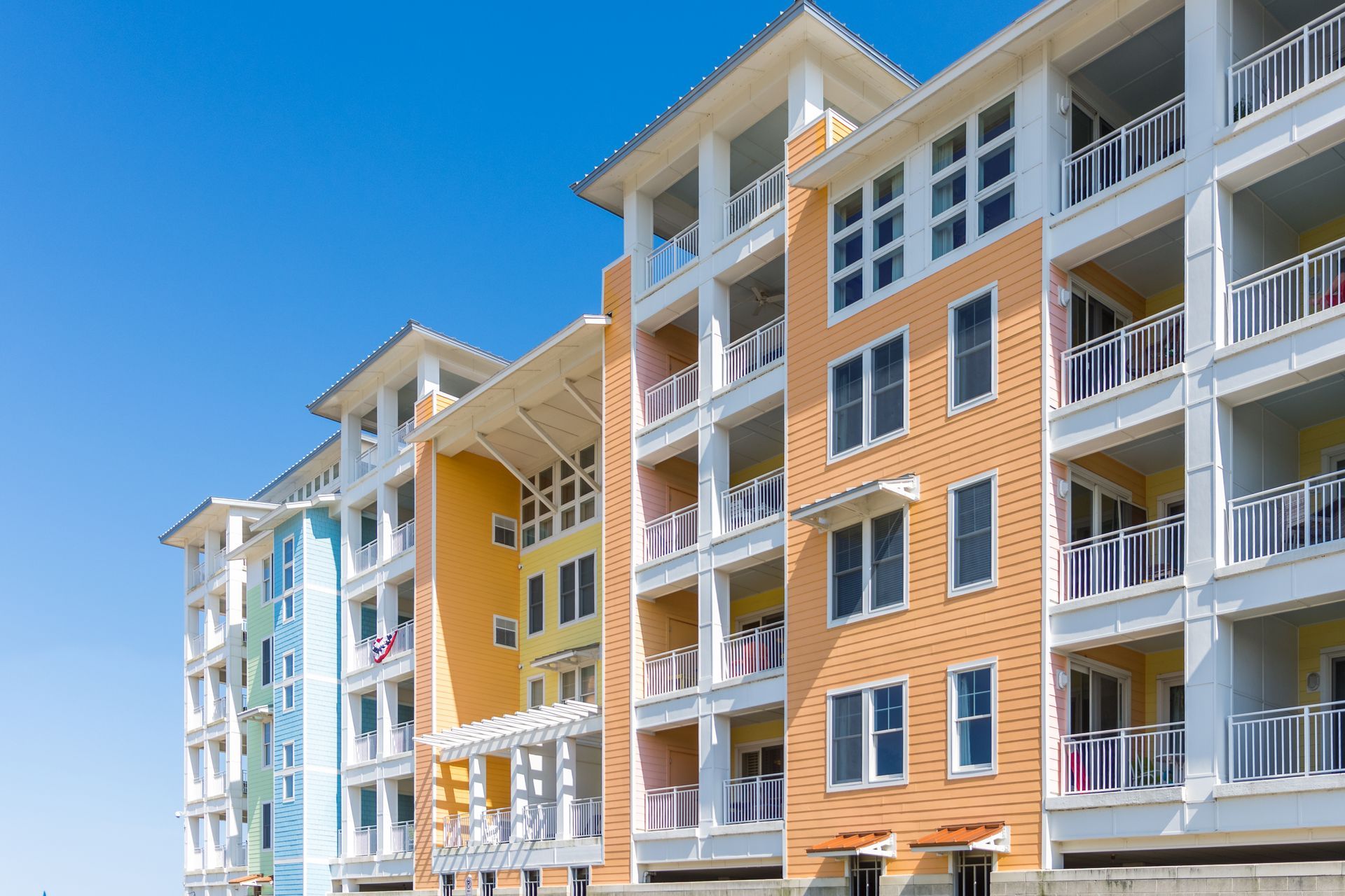 A row of apartment buildings with balconies and a blue sky in the background.