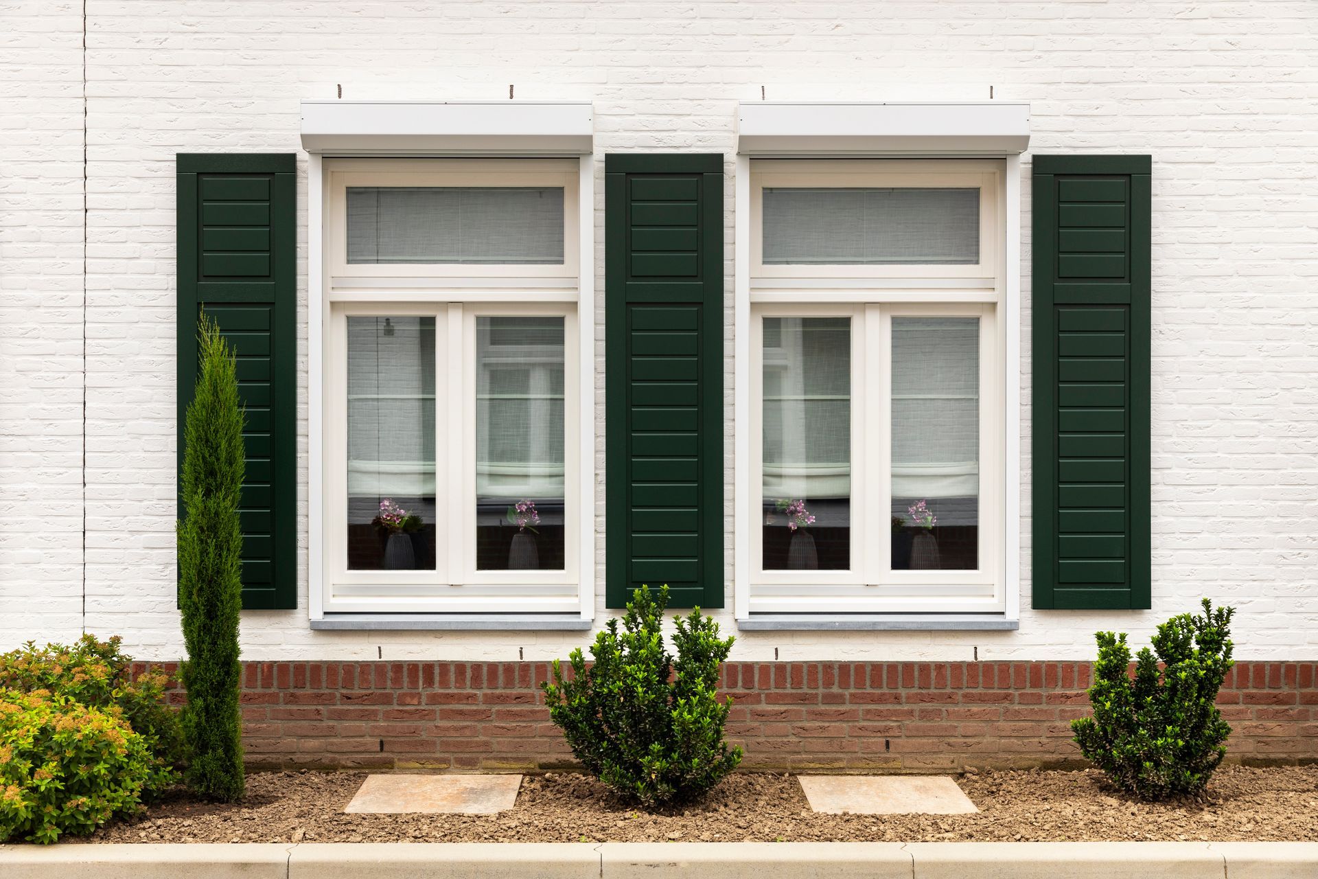 A white brick house with green shutters on the windows.