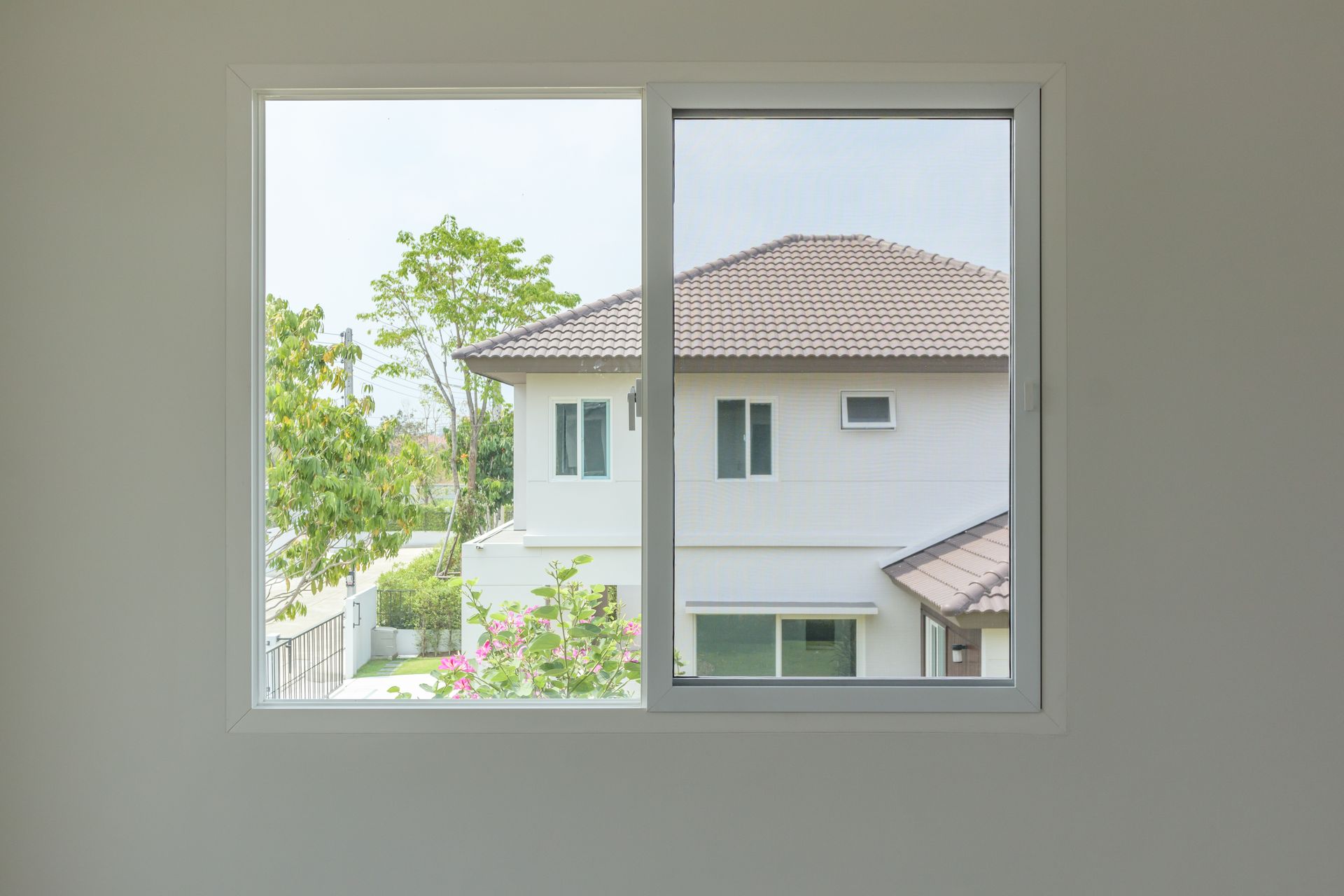 A white house is visible through a window in an empty room.