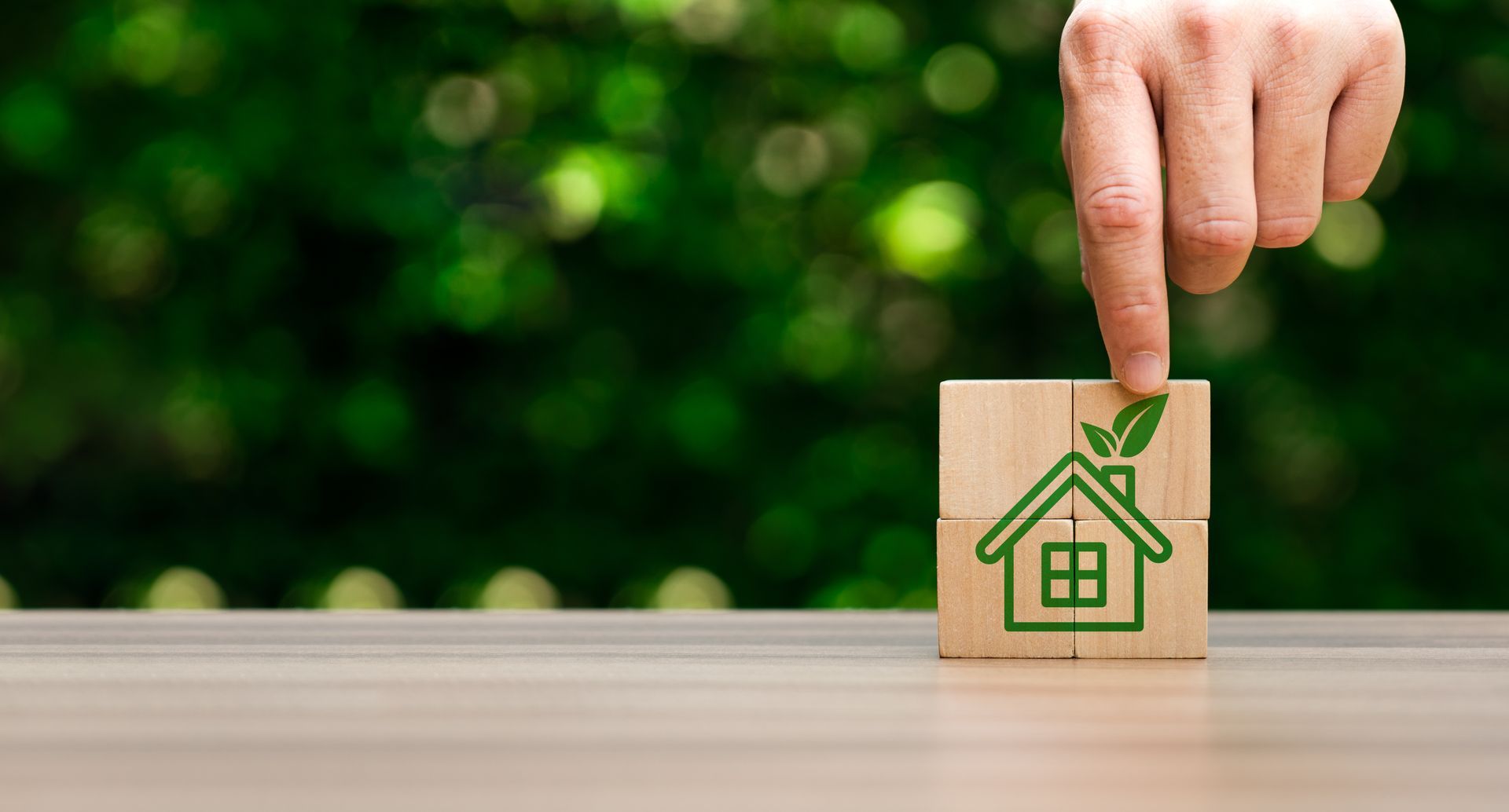 A person is pointing at a wooden block with a house drawn on it.