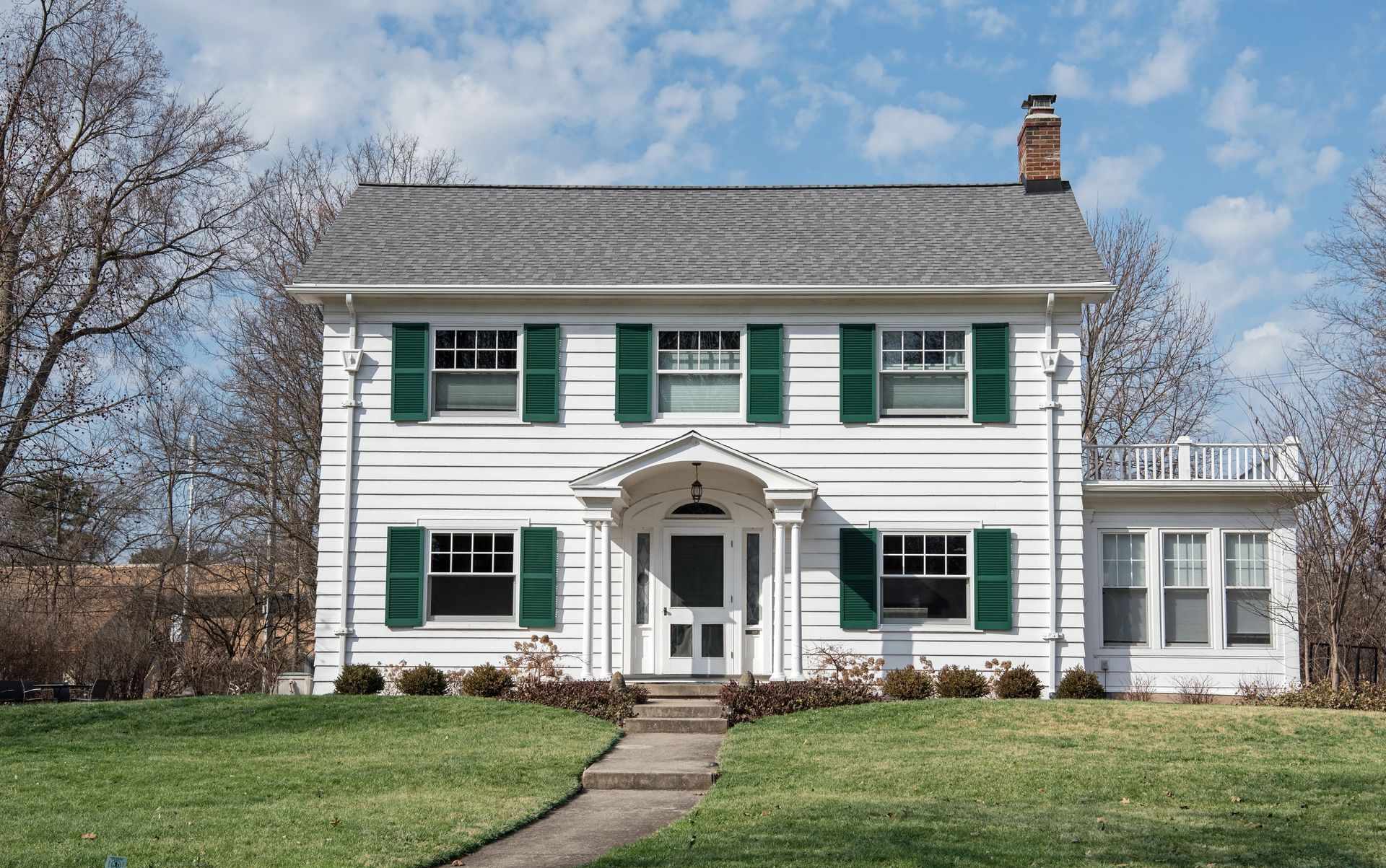 A large white house with green shutters on the windows