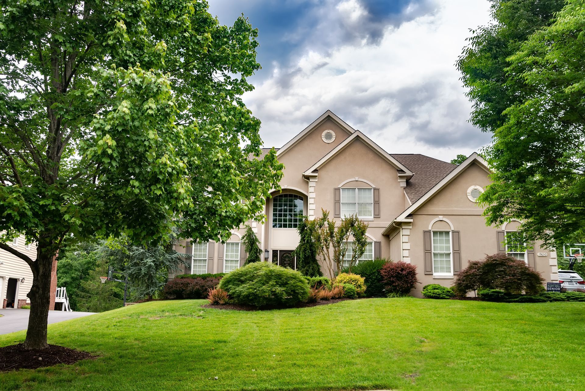 A large house with a lush green lawn and trees in front of it