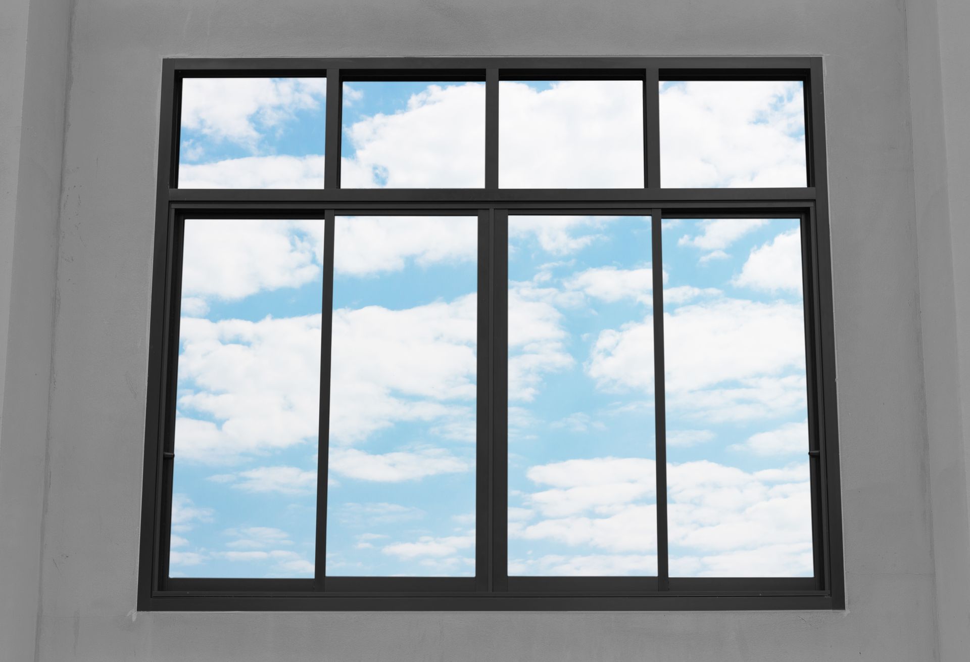 A window with a blue sky and clouds behind it.