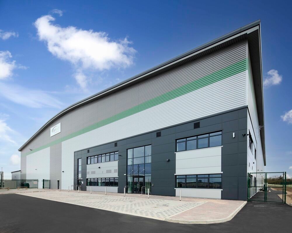 Modern industrial warehouse and office facility viewed from the side on a clear day.