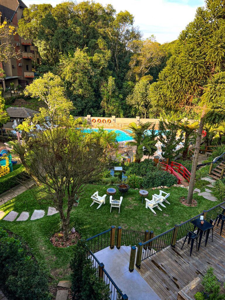 Espaço verde ao ar livre com árvores, piscina e áreas de estar.