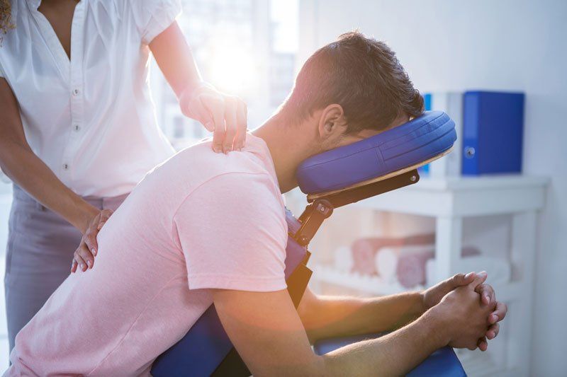 Physiotherapist giving back massage to a patient in clinic