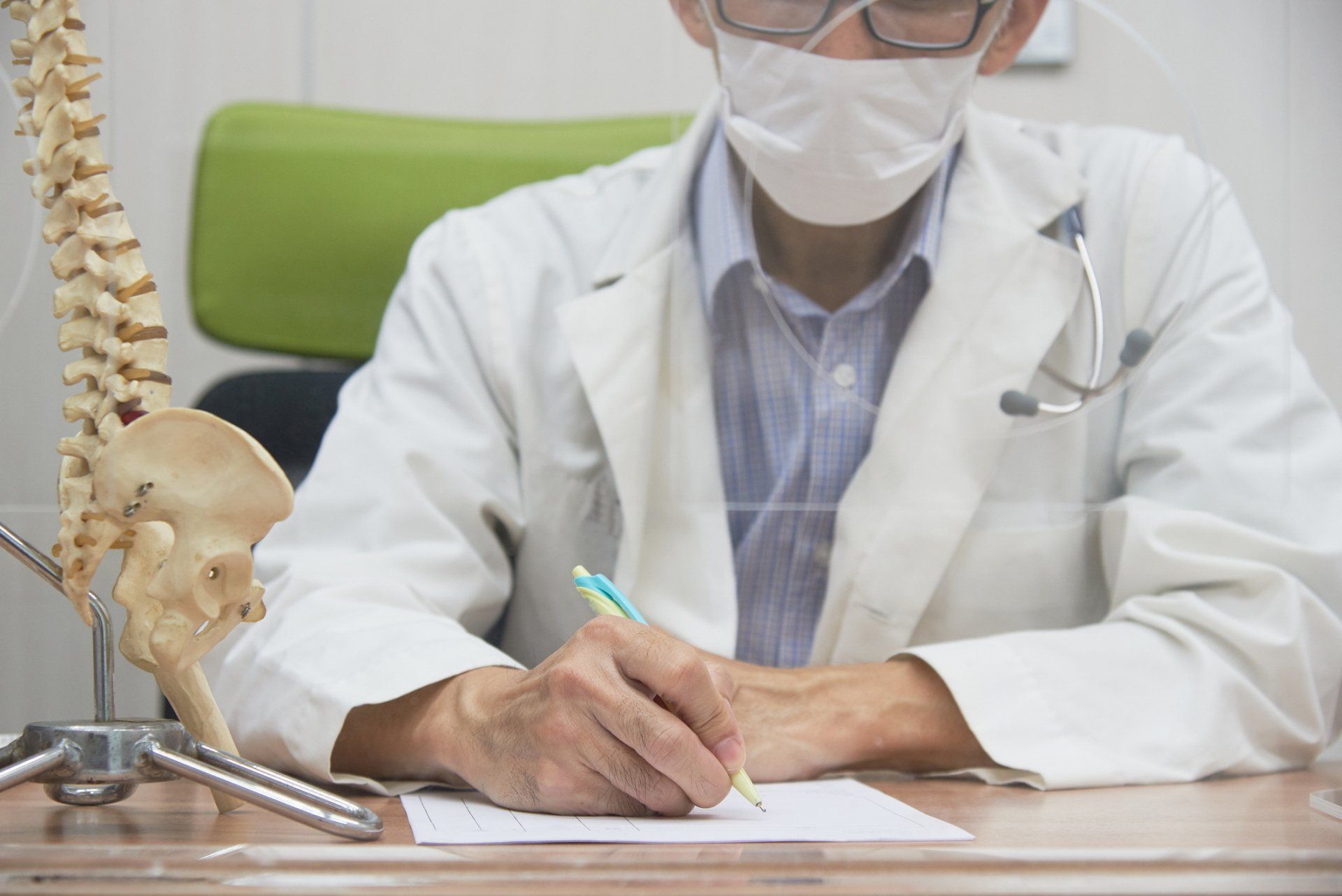 Male Doctor Wearing Face Mask Writing Prescription— Fair Oaks, CA — Corner Chiropractic Center