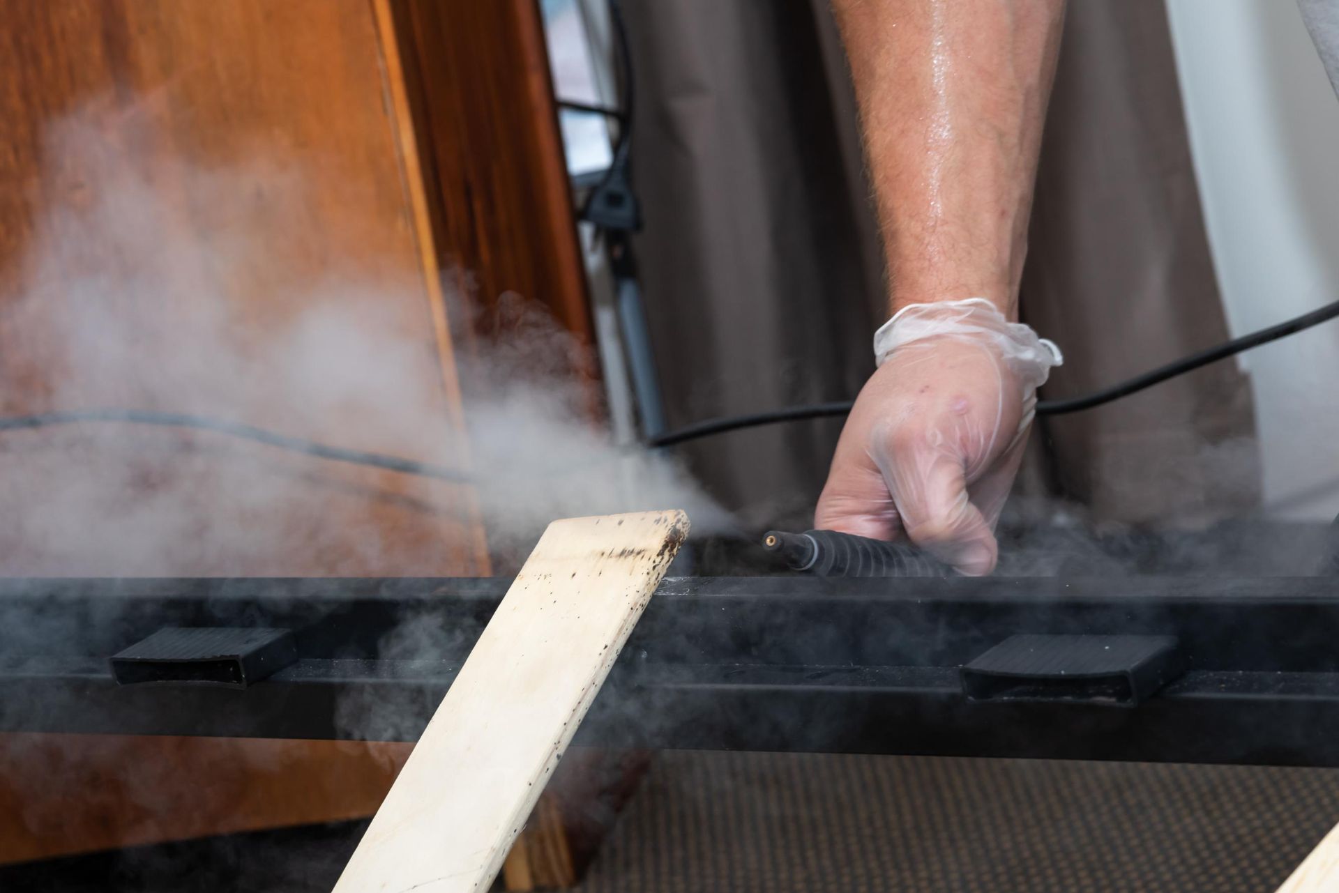 A Person is Cleaning a Wooden Table With a Steam Cleaner — Rozken Pest Control Services In Port Macquarie, NSW