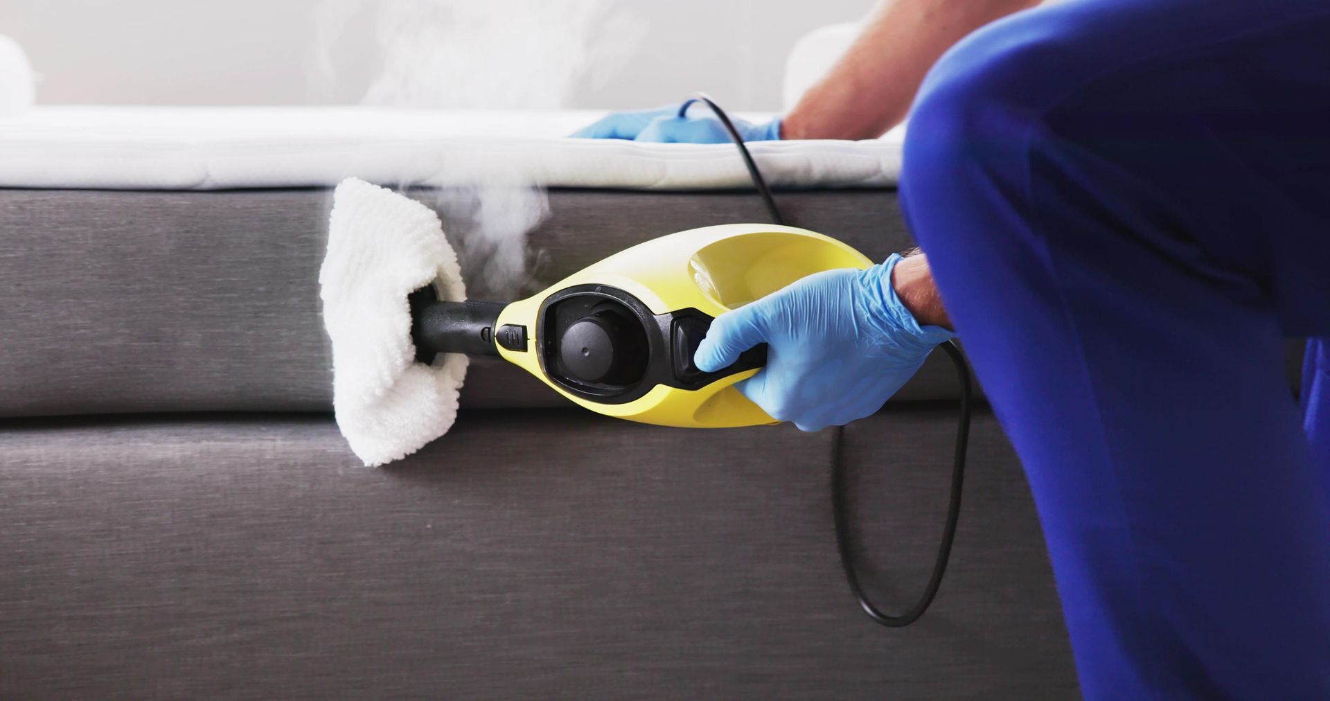 A Person is Cleaning a Mattress With a Steam Cleaner — Rozken Pest Control Services In Lake Cathie, NSW