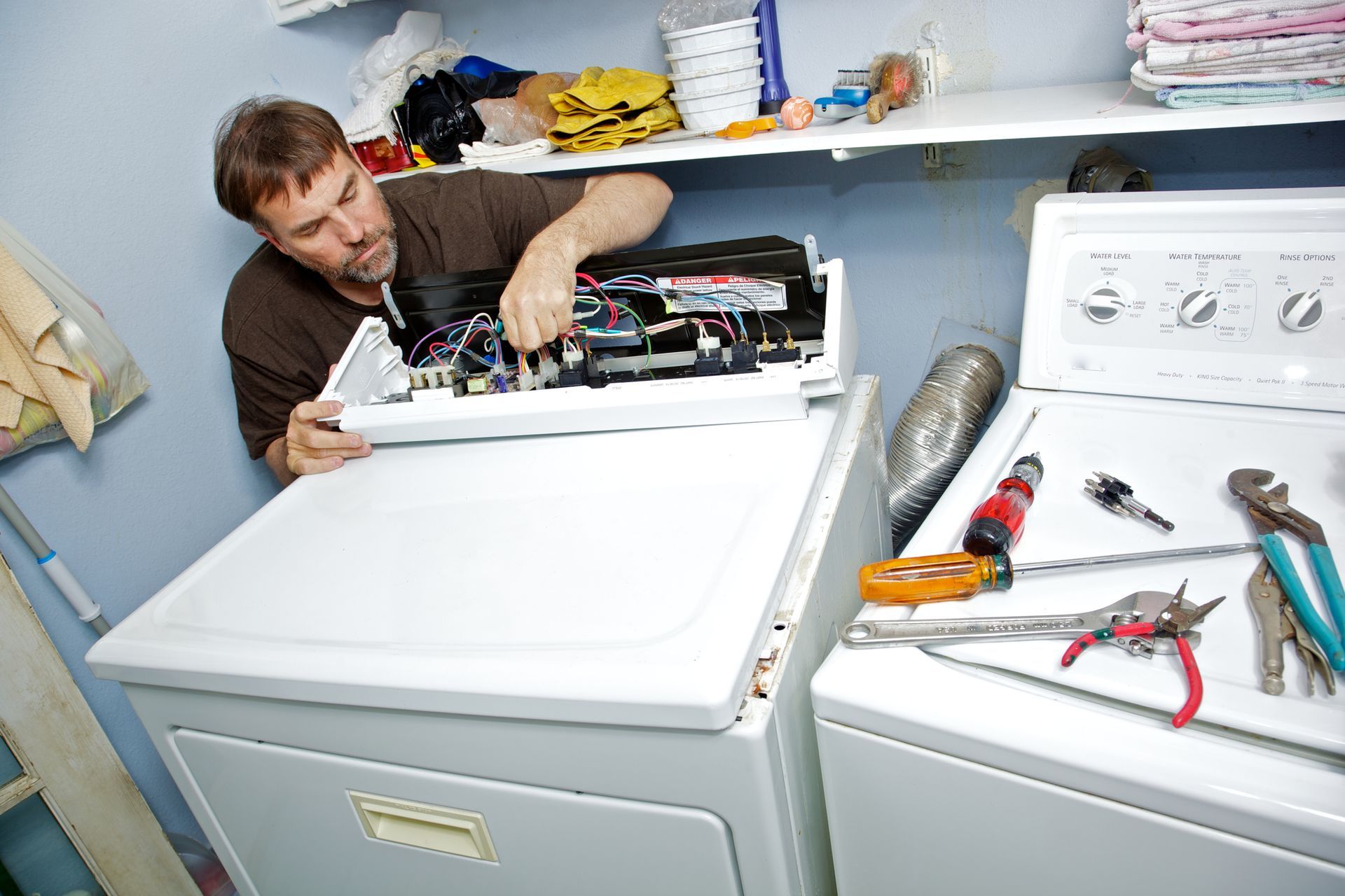 A man fixing an appliance at home, focusing on dryer repair in a cozy laundry room.